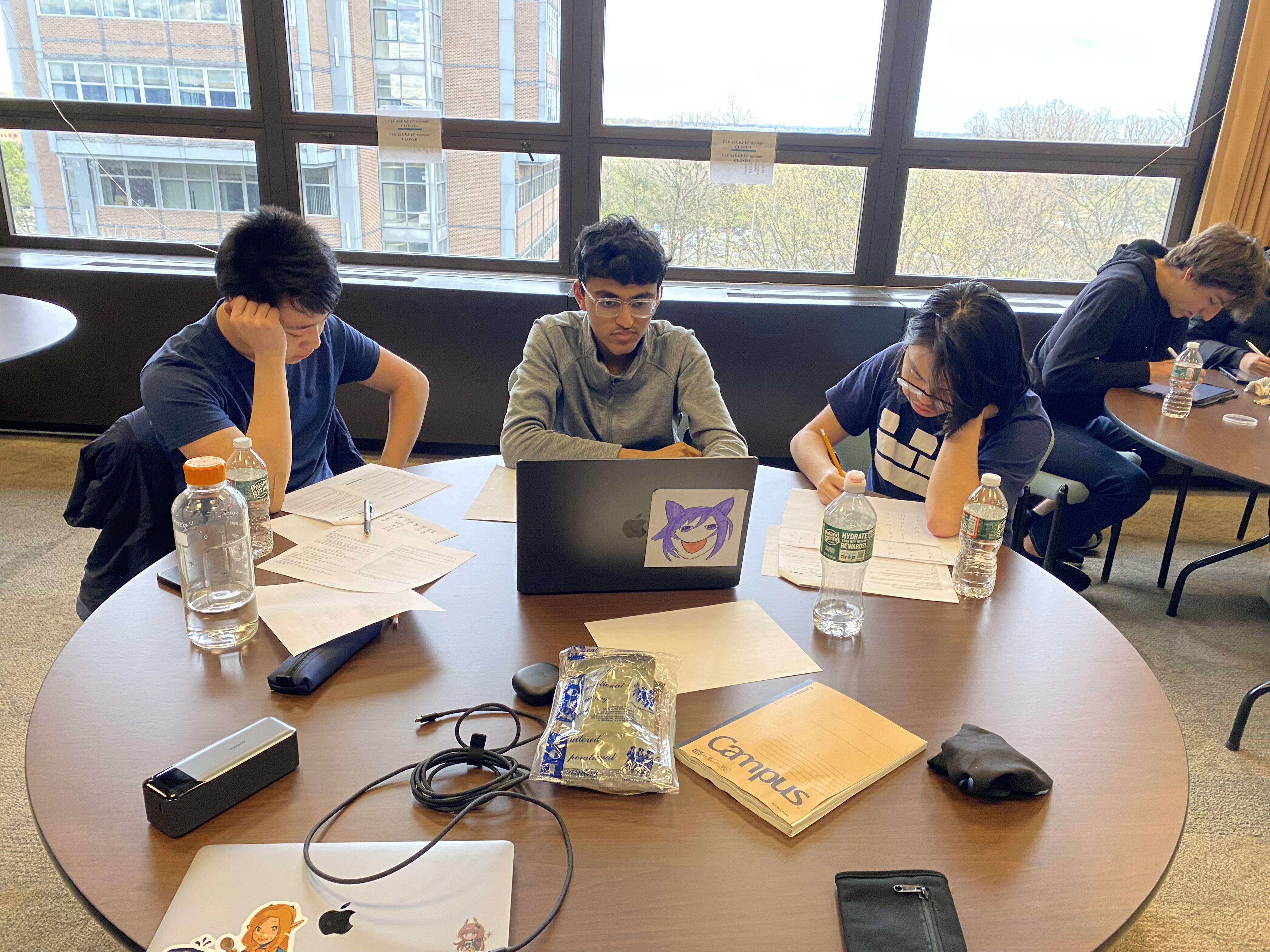 Team of students working at a round table by large windows