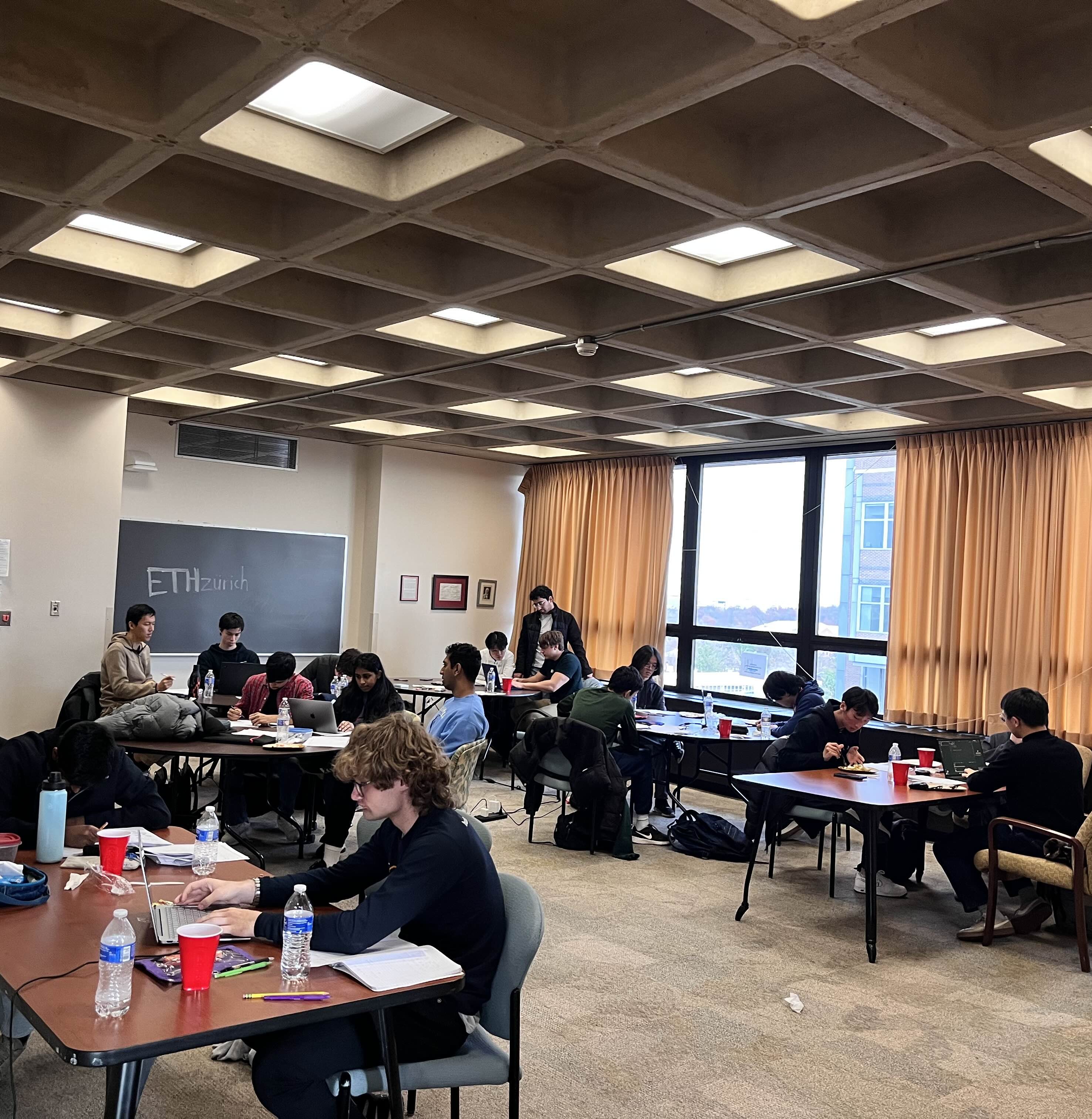 Wide view of contest teams working at tables in a classroom